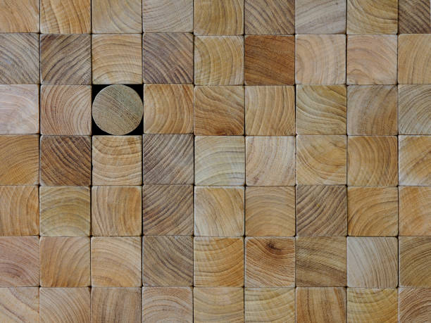 istock Many wood square blocks stacked up with one different round block within the background standing out from the crowd. 1007235208