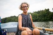 Smiling mature woman sitting on rowboat in lake