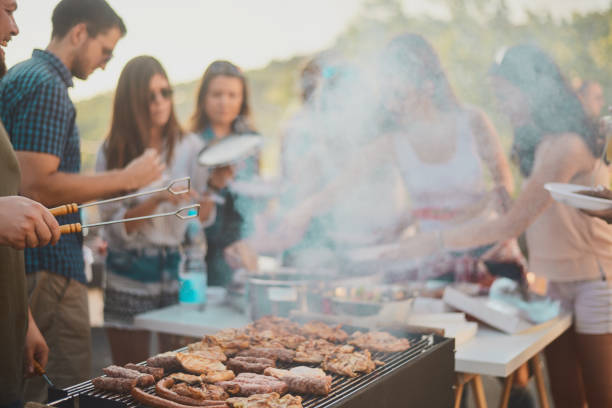 istock Group of people standing around grill. 1007239220