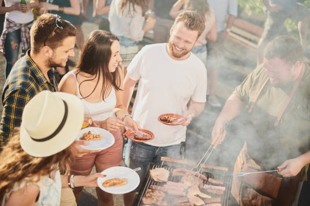 istock Group of people standing around grill. 1007239286