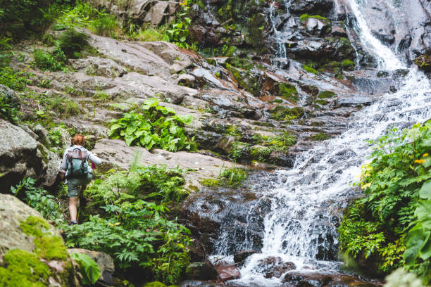 istock Backpacker woman is climbing near waterfall 1007239982