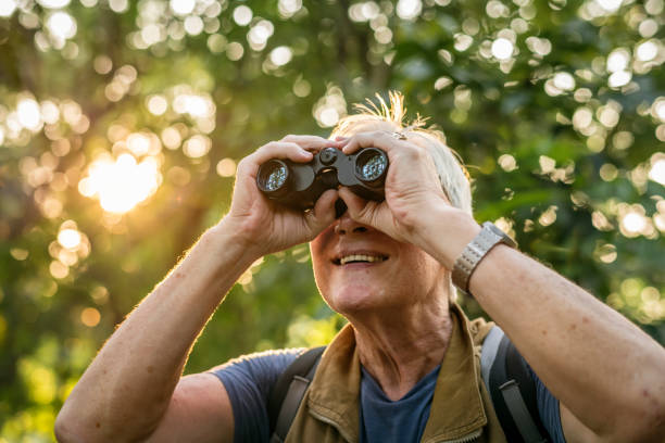 Elderly man watching birds with binoculars stock photo
