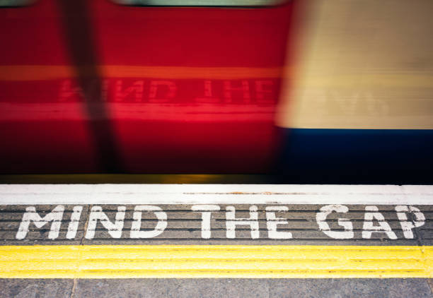 mind the gap знак и поезд лондонского метро - go английское слово стоковые фото и изображения