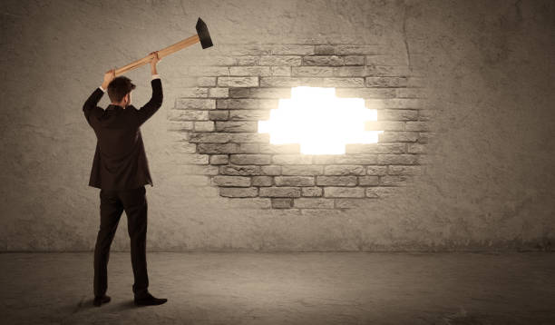 istock Business man hitting brick wall with hammer and opening a hole 1007254954
