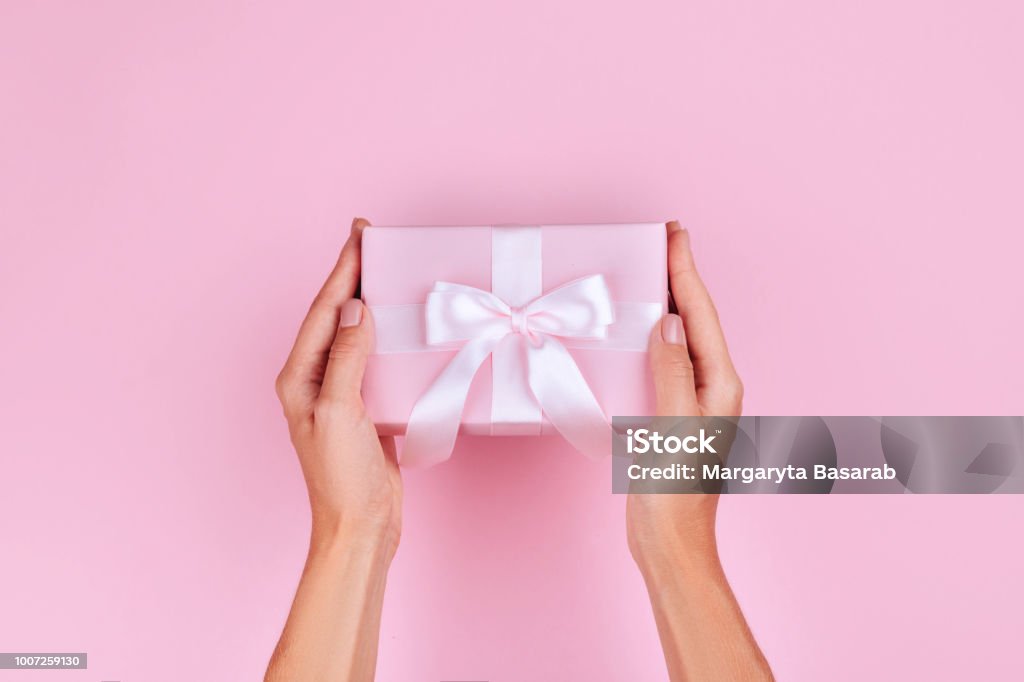 top view donna mano tenendo scatola regalo marrone su sfondo colore pastello rosa - Foto stock royalty-free di Regalo