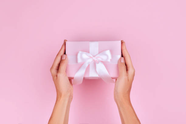 top view hand woman holding brown gift box on pink pastel color background top view hand woman holding brown gift box on pink pastel color background with space. hand holding gift stock pictures, royalty-free photos & images