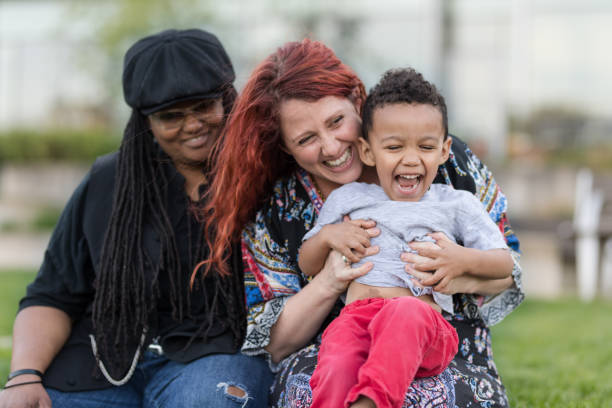 istock Two mothers holding their son on their laps outside 1007261948