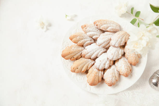 Homemade French cookies (cakes) Madeleine with jasmine tea on white background with fresh syringa floweres.