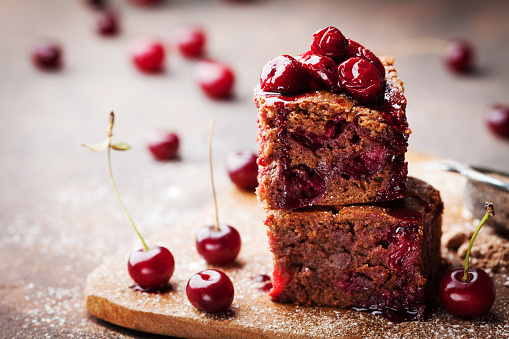 Chocolate brownie decorated with cherry. Homemade cake on wooden table. Macro.