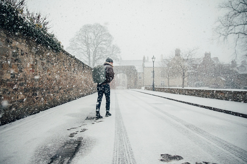 A young man walking in the snow in Northumberland, UK.