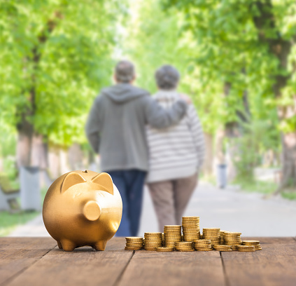 Gold piggy bank and coins in front of a senior couple