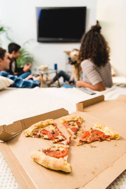 istock group of friends watching tv with pizza on foreground 1007295462