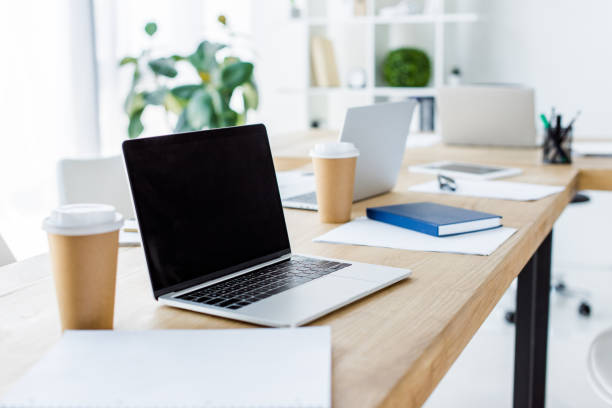 istock laptop with blank screen and disposable coffee cups on table in business office 1007305070