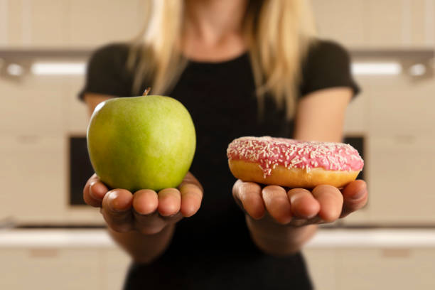 выбор между пончиком и яблоком - apple women green eating стоковые фото и изображения