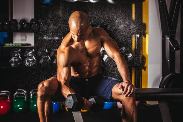 istock Strong muscular man exercising with dumbbell in gym 1007310688