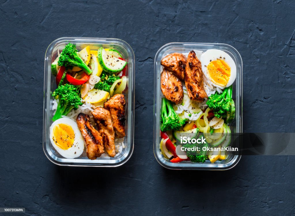 Rice, stewed vegetables, egg, teriyaki chicken - healthy balanced lunch box on a dark background, top view. Home food for office concept Lunch Box Stock Photo