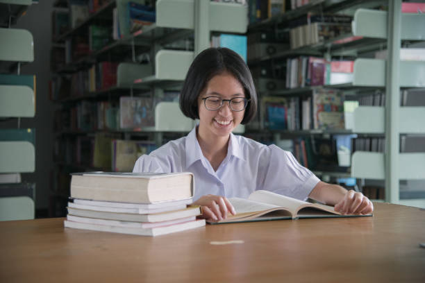 istock Asian student girl reading book in public library 1007314062