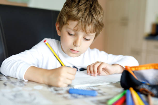 istock Tired kid boy at home making homework writing letters with colorful pens 1007318018