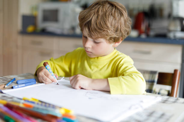 istock Tired kid boy at home making homework writing letters with colorful pens 1007318114