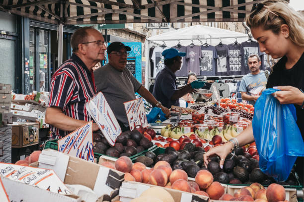 London, UK - July 22, 2018: Woman buying fresh fruit in Brick Lane, London. The street is the heart of the London's Bangladeshi-Sylheti community and is famous for its many curry houses.
