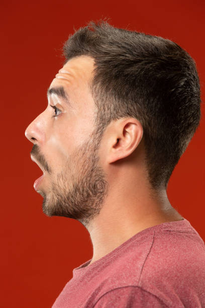 istock The young attractive man looking suprised isolated on red 1007329698