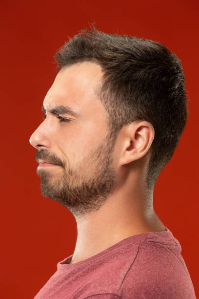 istock The young emotional angry man screaming on red studio background 1007330148