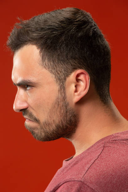 istock The young emotional angry man screaming on red studio background 1007330204