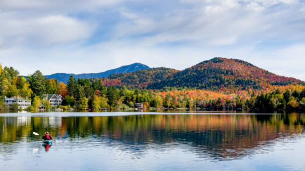 背景に山のカラフルな紅葉と晴れた秋の日の鏡湖レイク プラシッド、ニューヨークのパノラマ ビュー - adirondack mountains ストックフォトと画像