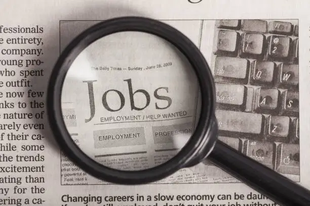 Magnifying glass over a newspaper classified section with Job