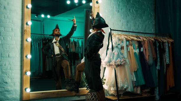 Man in pirate costume rehearsing scene Back view of man wearing costume of pirate and standing in front of mirror in dressing room practicing scene from performance theatre mirror stock pictures, royalty-free photos & images