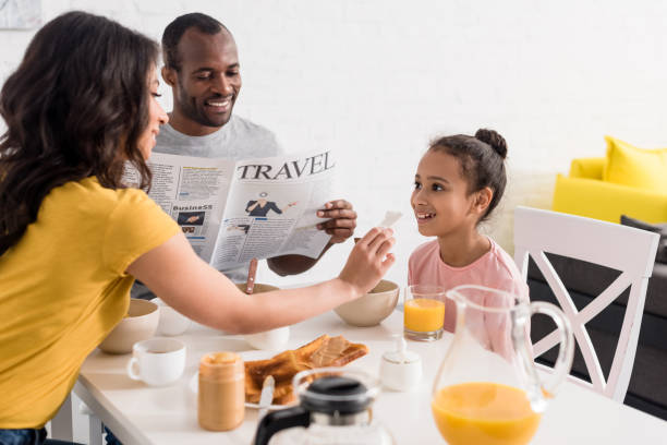 母父キッチンで新聞を読みながら朝食後少し娘の顔を拭く - newspaper reading mother women ストックフォトと画像