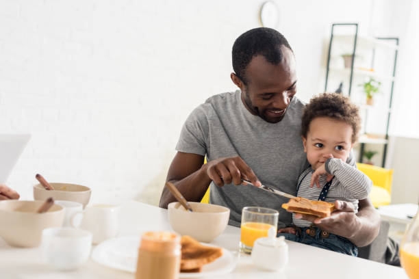 istock father applying peanut butter on toast for little son 1007345732
