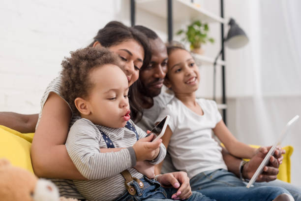 istock happy young family spending time together with devices on couch 1007345772