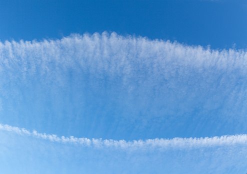 clouds formed from the inverse trail of an airplane under the influence of a strong wind