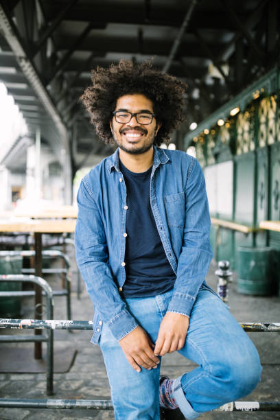 istock Young african man sitting on railing outside 1007371176