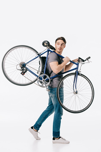 handsome student holding bicycle on shoulder isolated on white