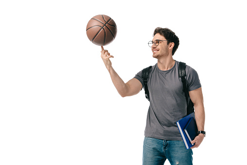 happy handsome student spinning basketball ball on finger isolated on white