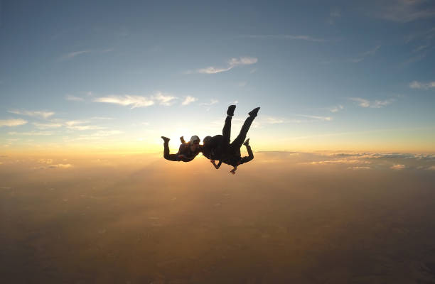 paracadutisti che si divertono al tramonto - skydiving parachuting extreme sports airplane foto e immagini stock