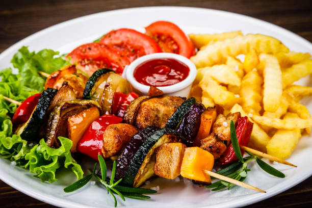 istock Kebabs - grilled meat, chips and vegetables on wooden background 1007416240