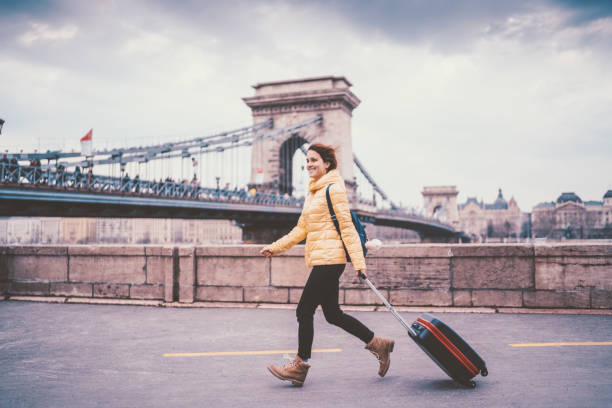 Young woman traveling in Europe Smiling woman pulling a suitcase and enjoying Budapest expatriate photos stock pictures, royalty-free photos & images