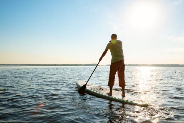 istock Man paddling on a SUP board along a large river 1007419914