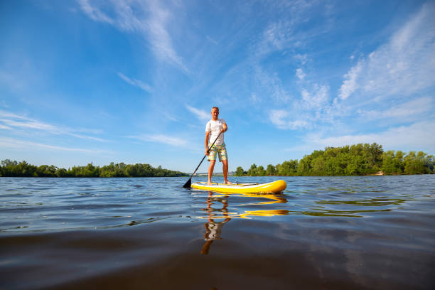 istock Joyful man paddling on a SUP board on large river 1007419920