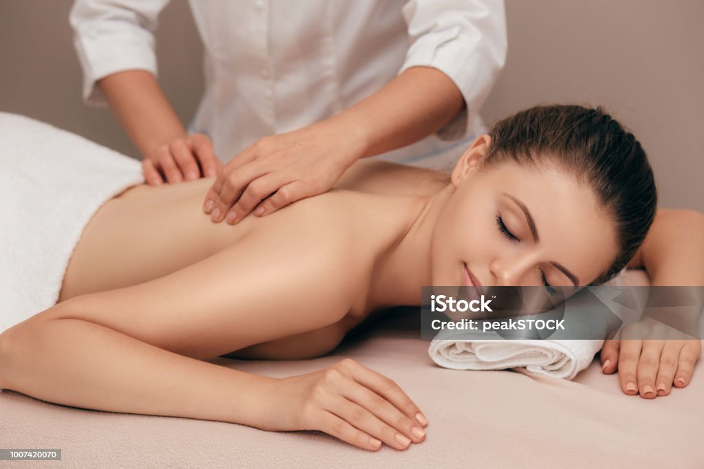 giovane donna che riceve un massaggio al salone spa - Foto stock royalty-free di Massaggiare