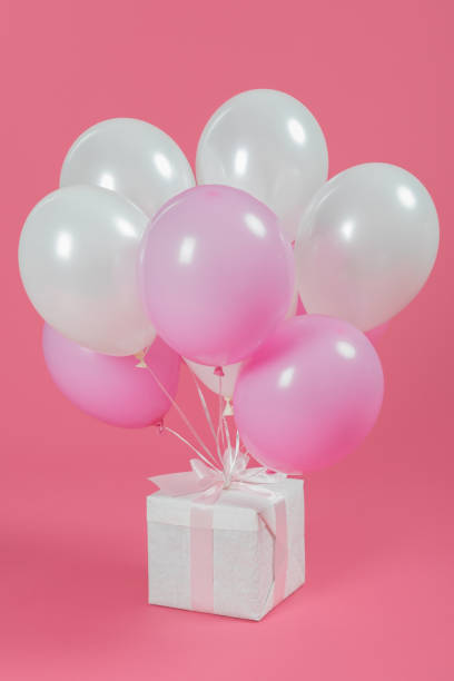 istock Presents with white and pink balloons on pink background 1007425598