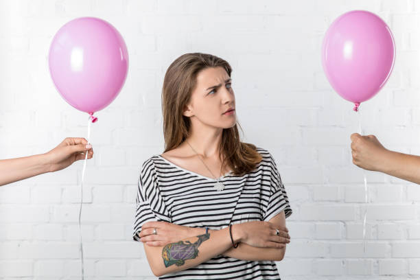 istock Thoughtful young woman looking at hand holding balloon on white brick wall background 1007425728