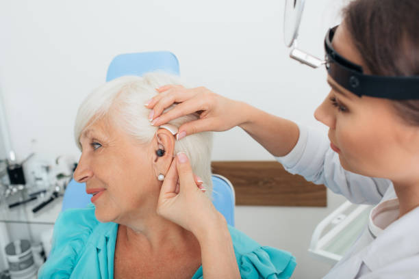 istock doctor helping elderly woman inserting hearing aid 1007426124