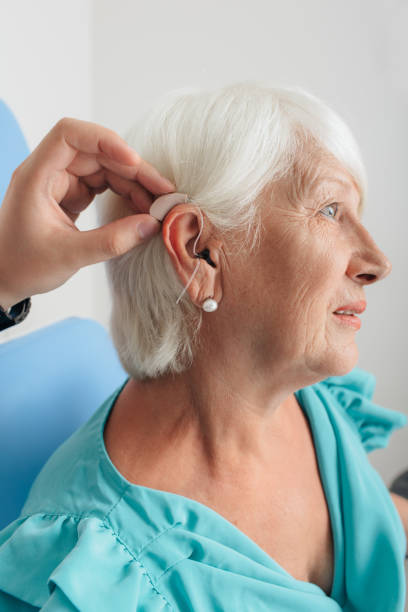 adjusting of a hearing aid for an aged woman adjusting of a hearing aid for an elderly woman assistive technology photos stock pictures, royalty-free photos & images