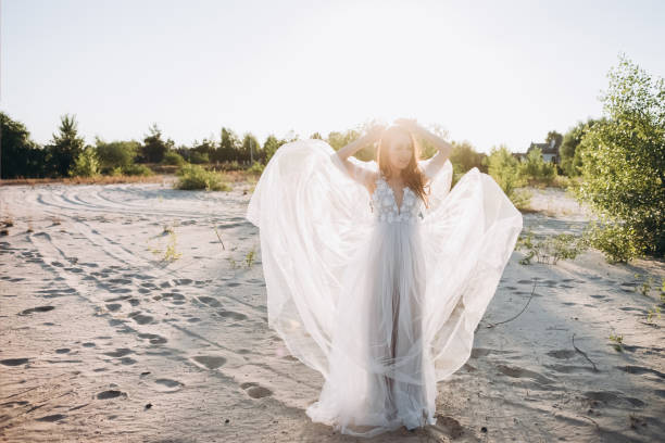 istock young attractive bride in wedding dress posing on beach with back light 1007441342