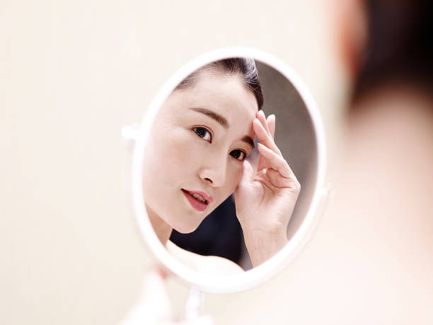 istock young asian woman looking into mirror 1007441592