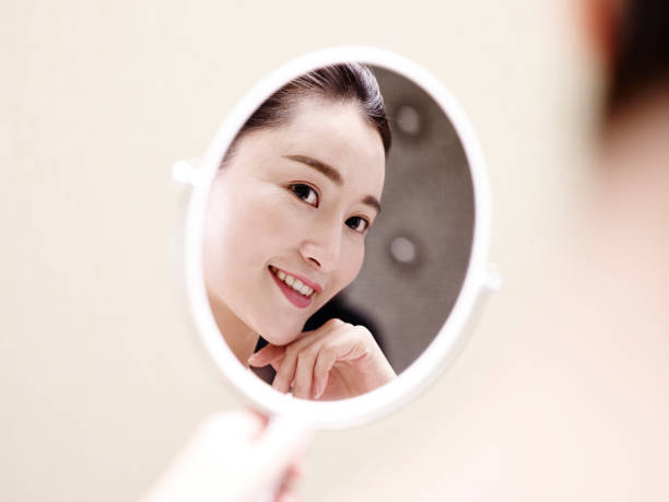 istock young asian woman looking into mirror 1007441602